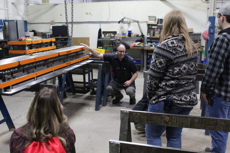 Toolroom worker giving a student tour of a progressive stamping die